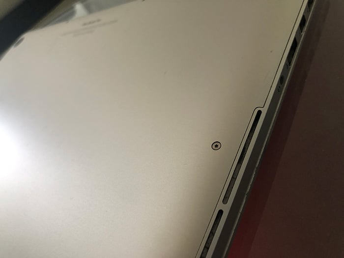 A parte inferior de um MacBook Pro, mostrando os parafusos que fixam a carcaça